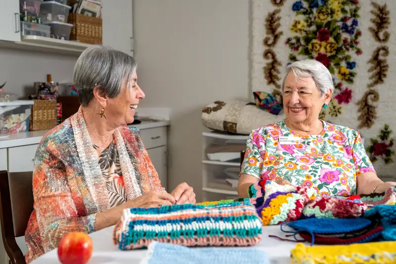 Two women enjoy a crafting activity in a bright room