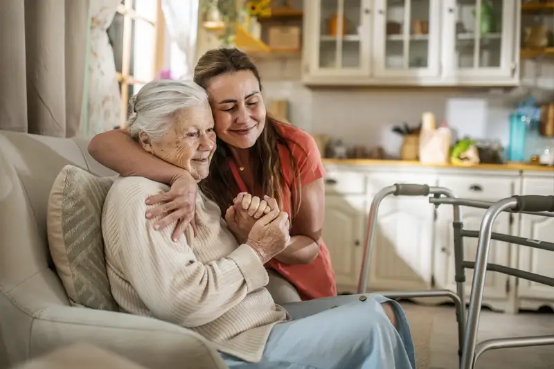A caregiver embracing an elderly resident in a cozy living area