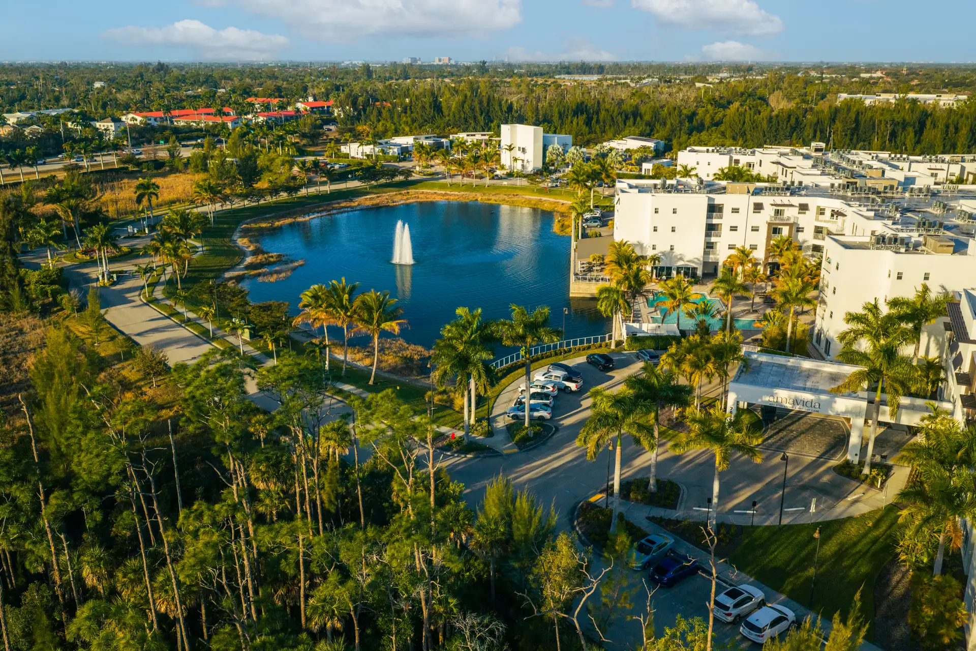 Aerial view of a senior living facility with a pond and landscaping