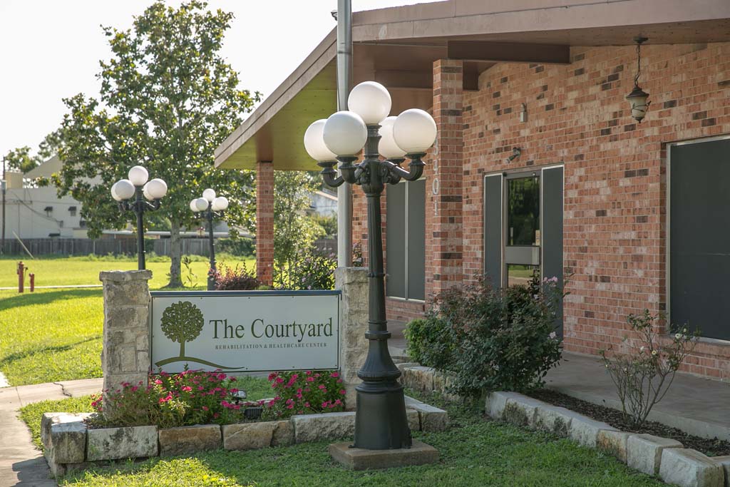 Exterior view of The Courtyard facility with landscaping.
