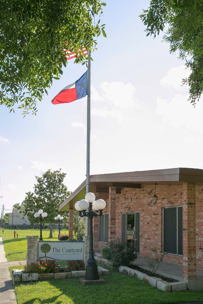 Exterior view of The Courtyard with flag and sign.