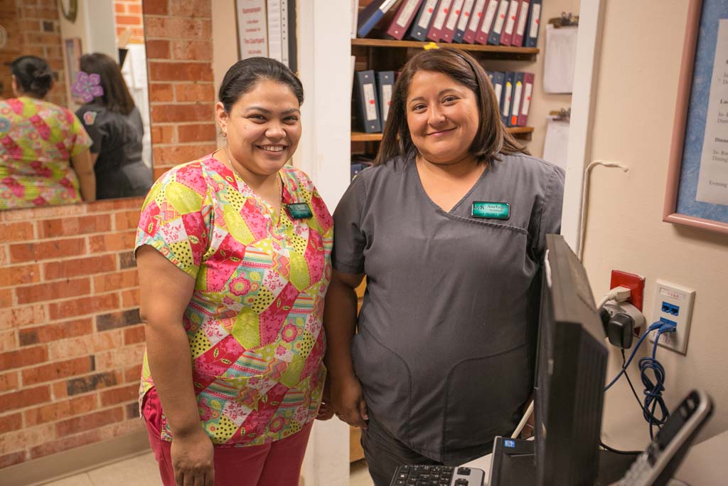 Two staff members smiling in an office setting.