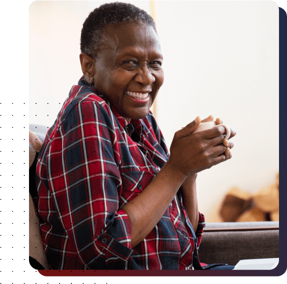 Smiling resident holding a cup in a cozy interior.