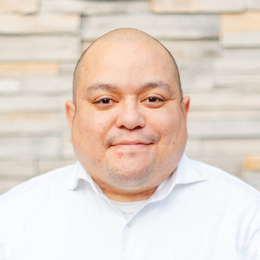 Close-up portrait of a man smiling in front of a stone wall