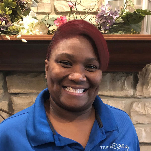 Staff member smiling in front of a decorative backdrop