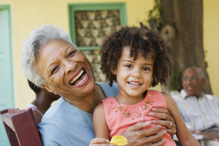 An elderly woman and a young girl laughing together outdoors