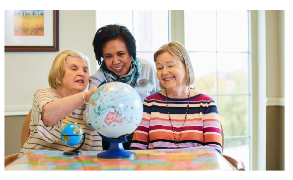 Residents and staff engaging around a globe in a common area