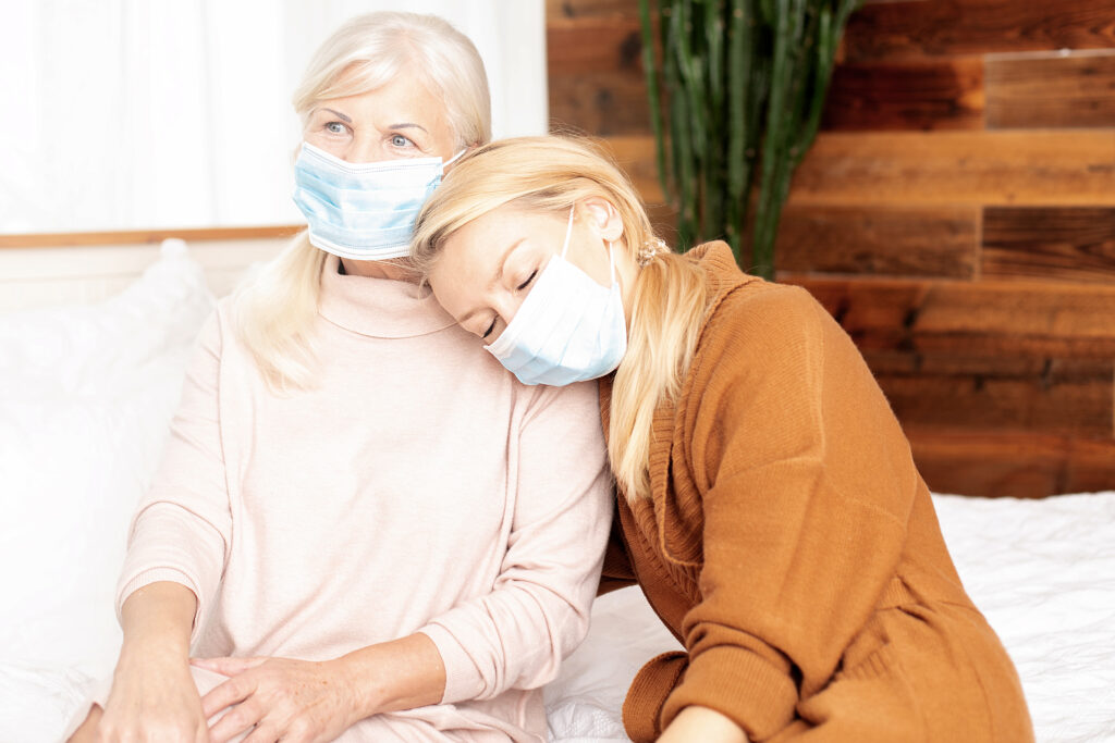 Two women wearing masks in a cozy indoor setting