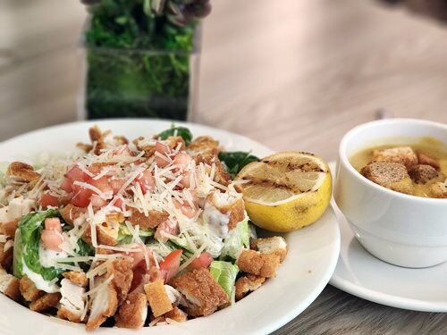 A plate of Caesar salad with chicken and soup