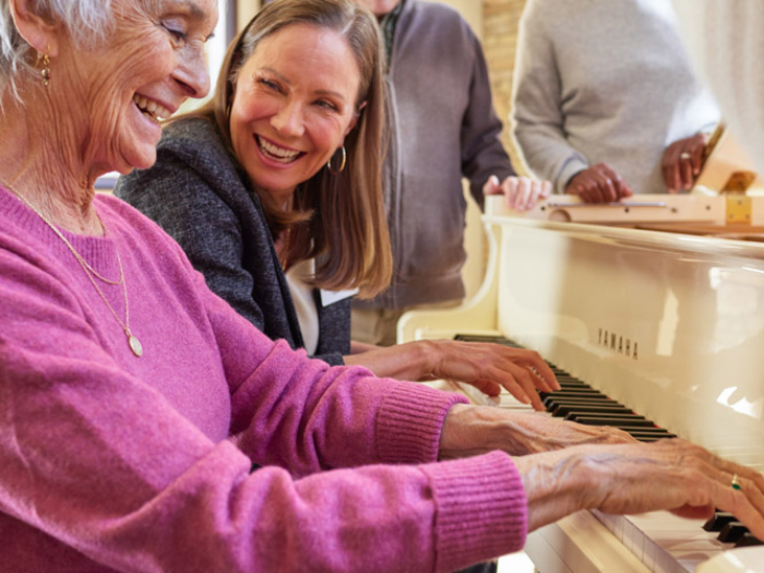 Resident playing piano with staff member