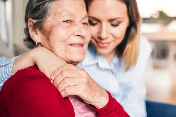 A young woman embracing an elderly woman indoors