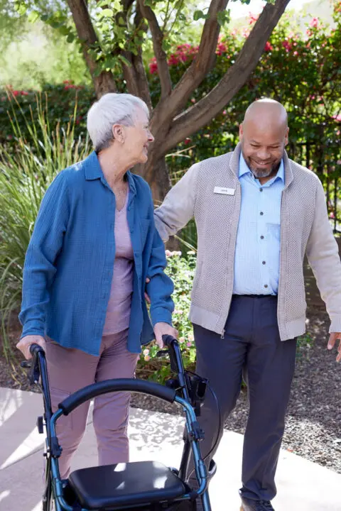 Staff assisting a resident outside with a walker