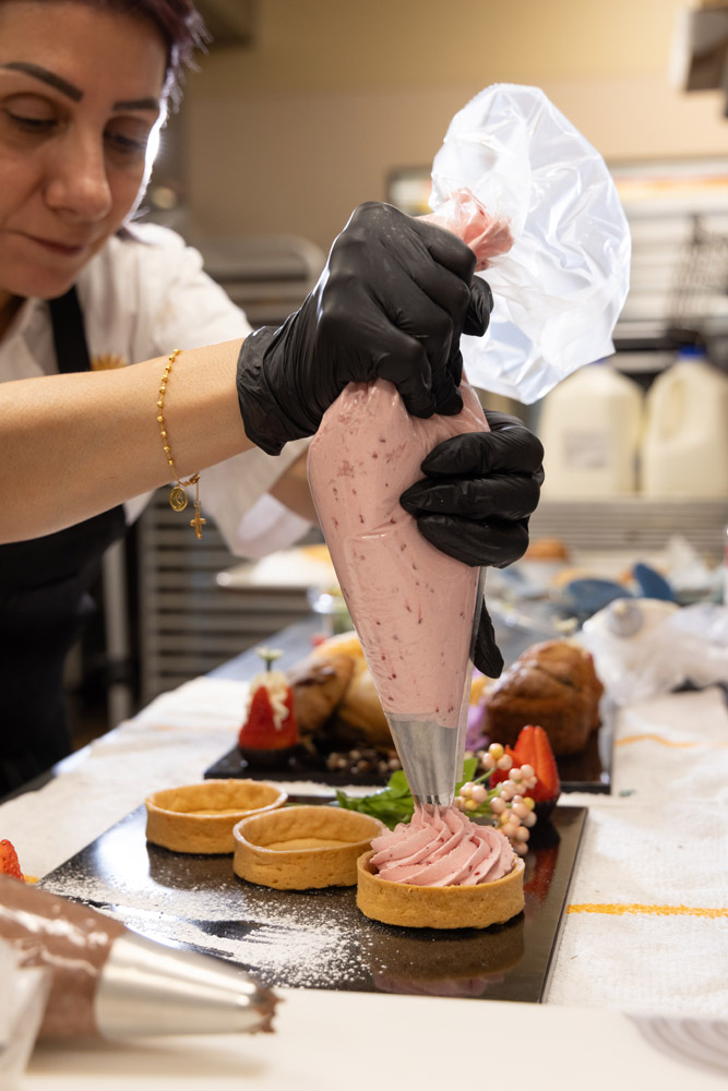 Staff member decorating a dessert in the kitchen