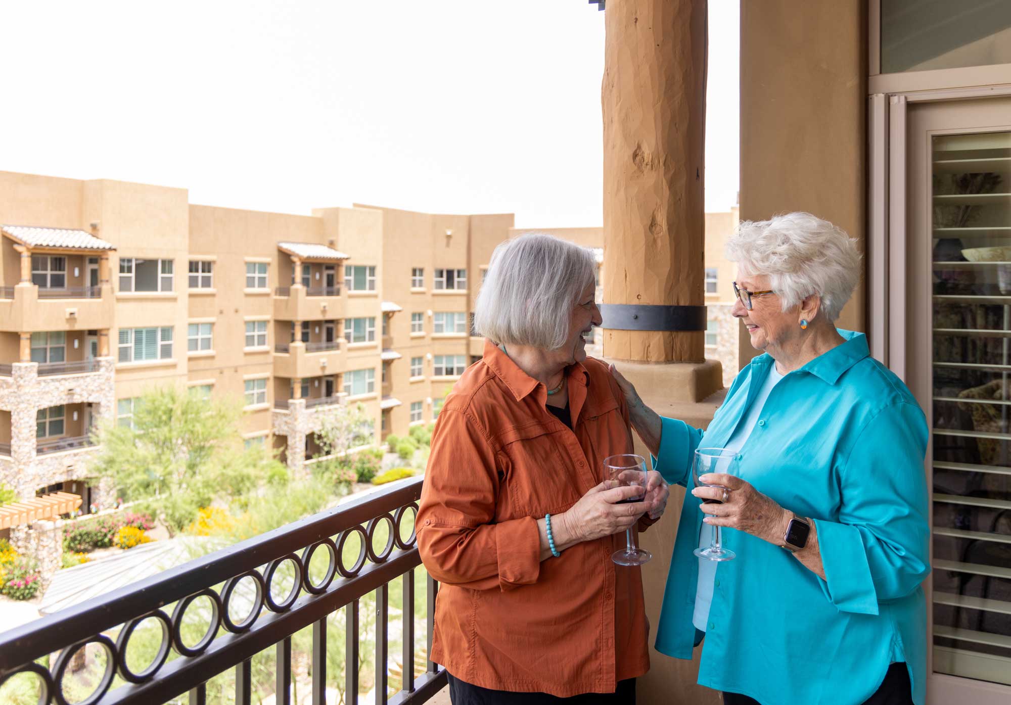 Two residents enjoying drinks on a balcony at the facility