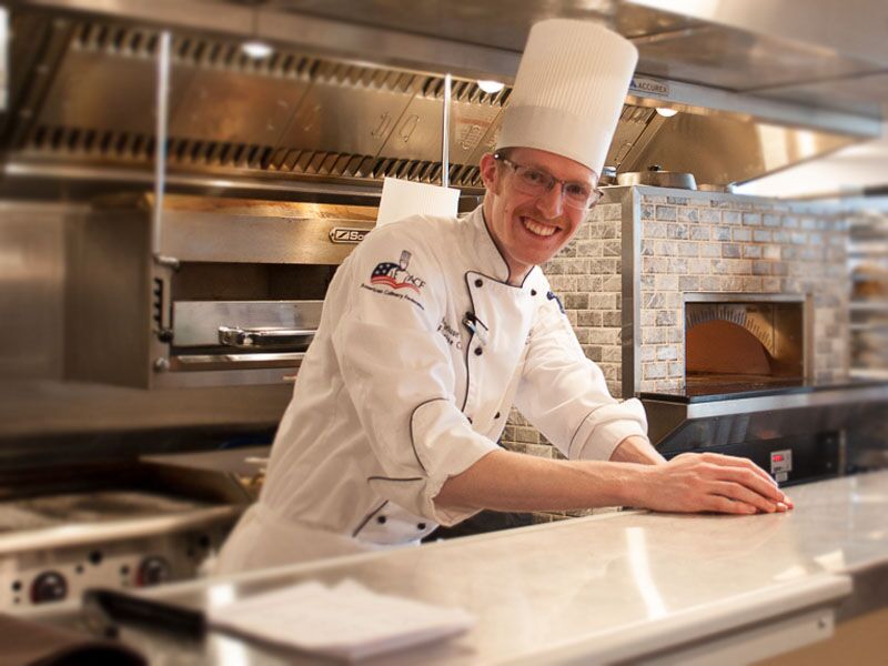 A chef smiling in a well-equipped kitchen