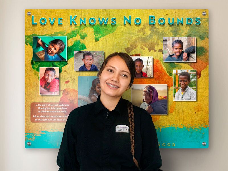 Staff member posing in front of a colorful display board