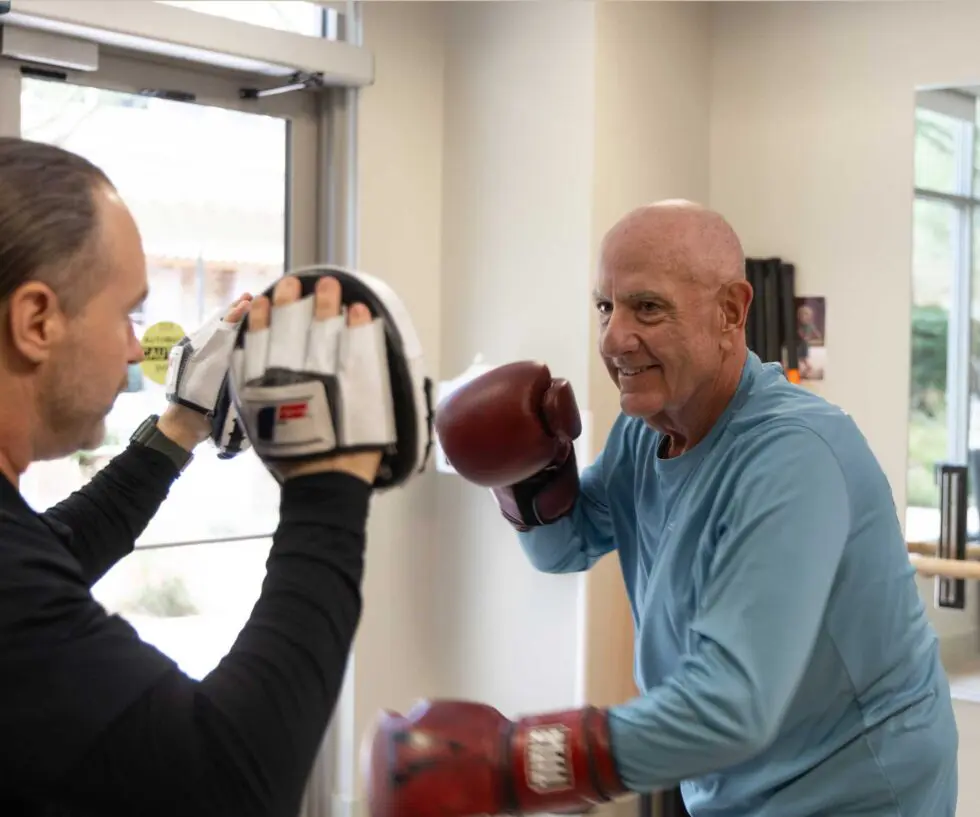 Senior resident boxing with staff member in activity room