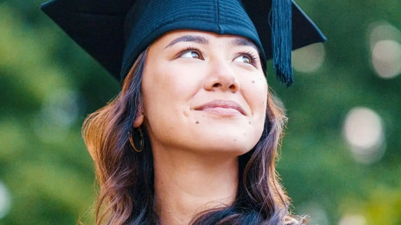 A young woman in a graduation cap gazing upwards