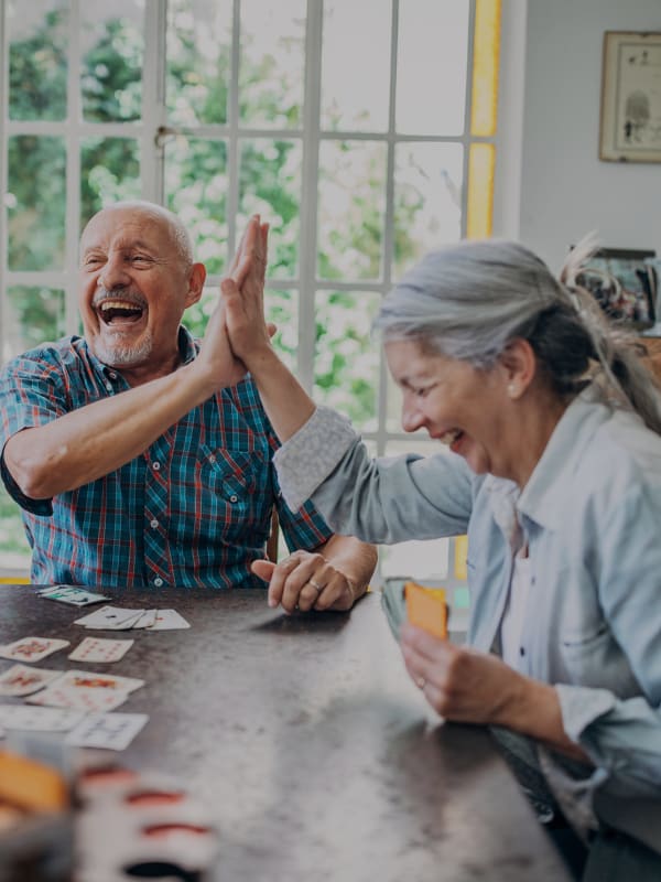 Two seniors enjoying a card game and laughing together.