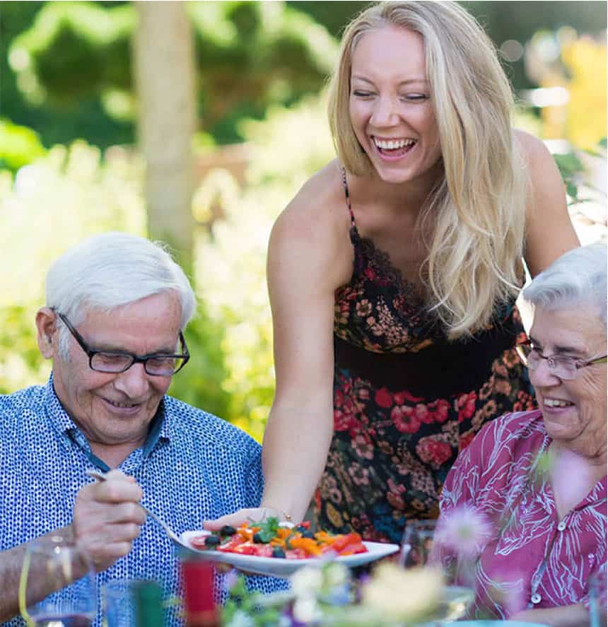 Residents enjoying a meal outdoors with a staff member