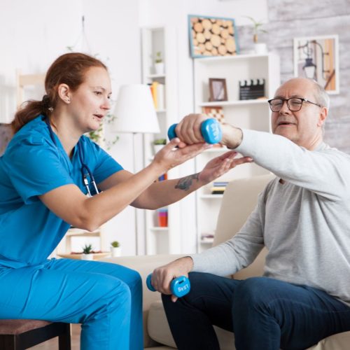 A healthcare worker assists a senior with weights.