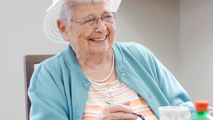 Smiling elderly woman wearing a hat indoors.