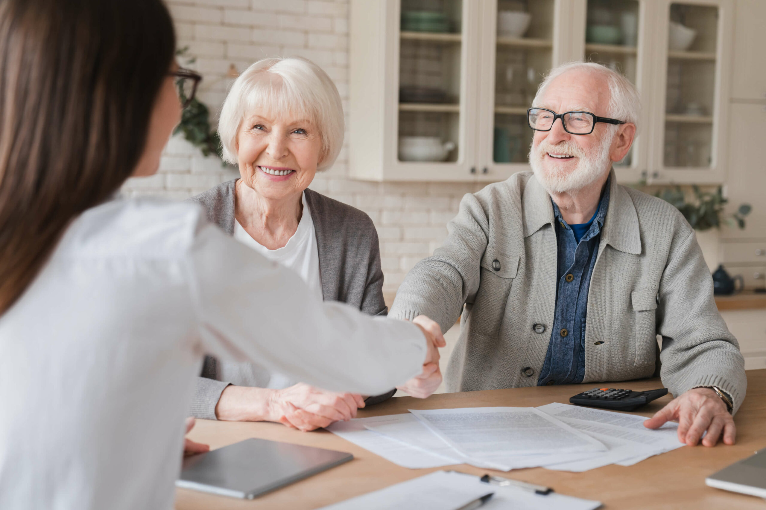 Two seniors happily interacting with a staff member.