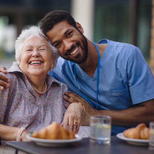 Patient and caregiver enjoying a meal together outdoors.