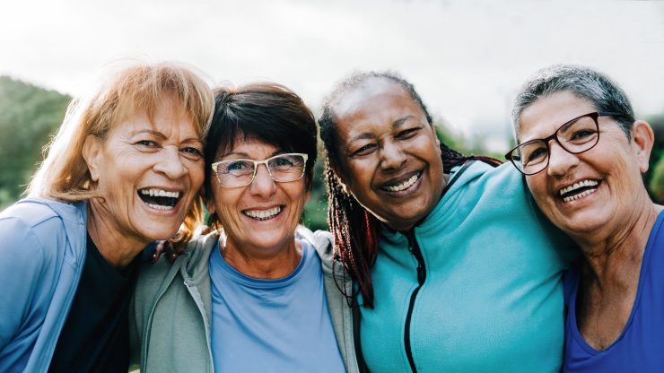 Four happy women enjoying time together outdoors.