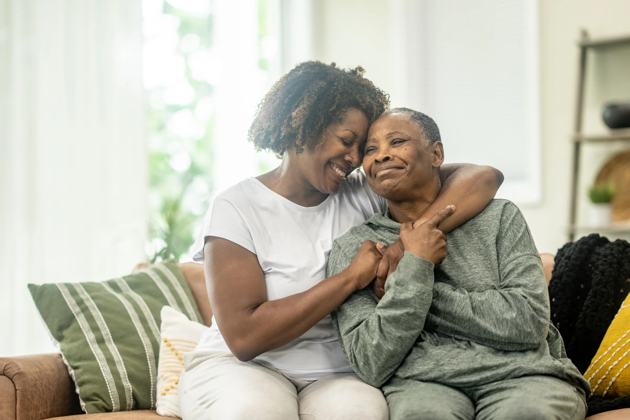 Two women sharing a warm embrace on a couch.