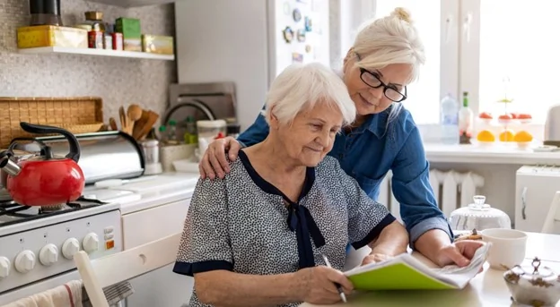 A caregiver assisting a senior in a kitchen