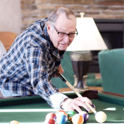 Resident enjoying a game of billiards indoors.