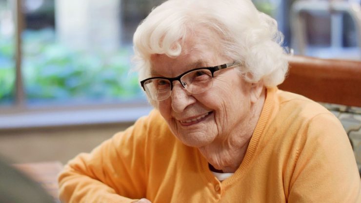 Smiling elderly woman in a care facility setting.
