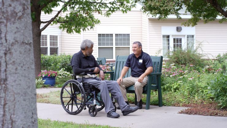 Resident and staff engaging outdoors in a garden.