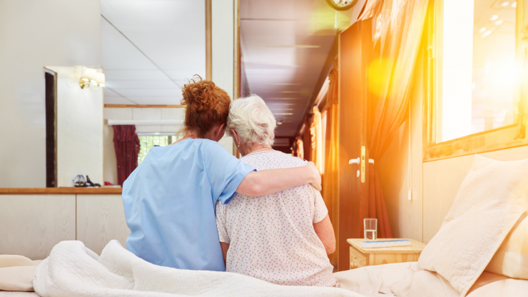 Caregiver comforting a senior resident in their room.