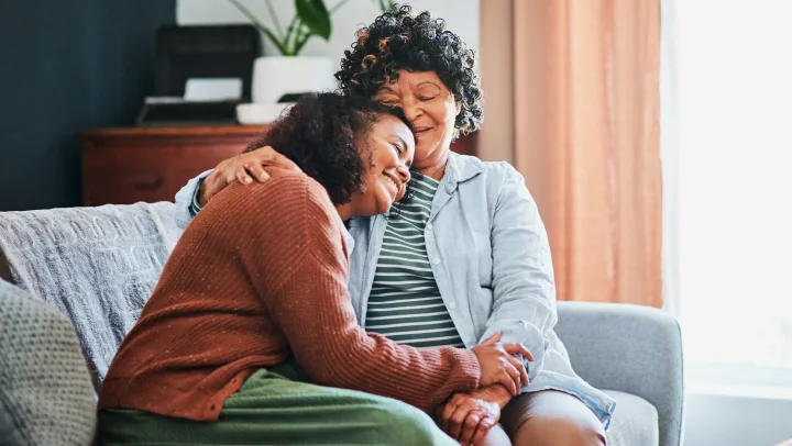 Two women sharing a warm embrace on a couch.
