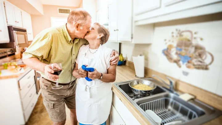 A couple cooking together in a kitchen.