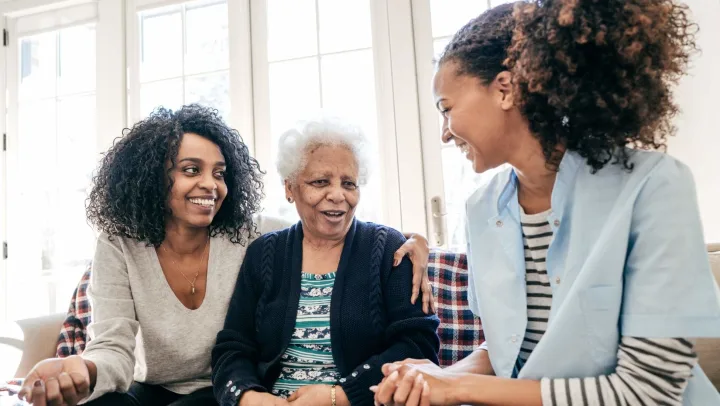 Smiling women engaging with an elder in a bright room.