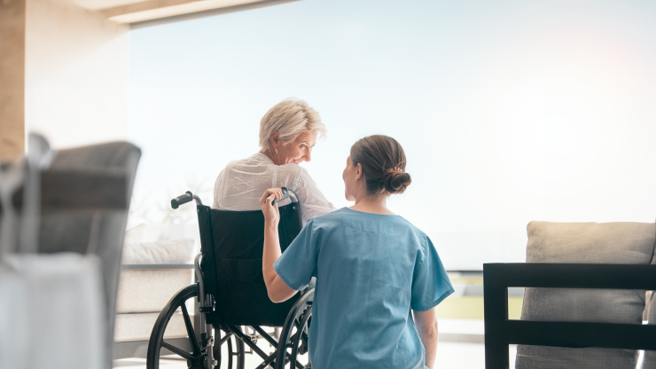 Care staff assisting a resident in a wheelchair.