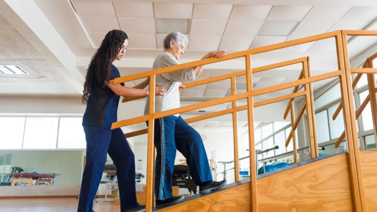 Staff assisting a resident with rehabilitation stairs.