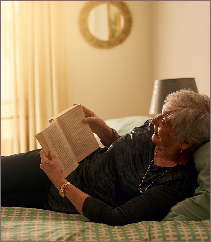 Senior woman reading a book in her room
