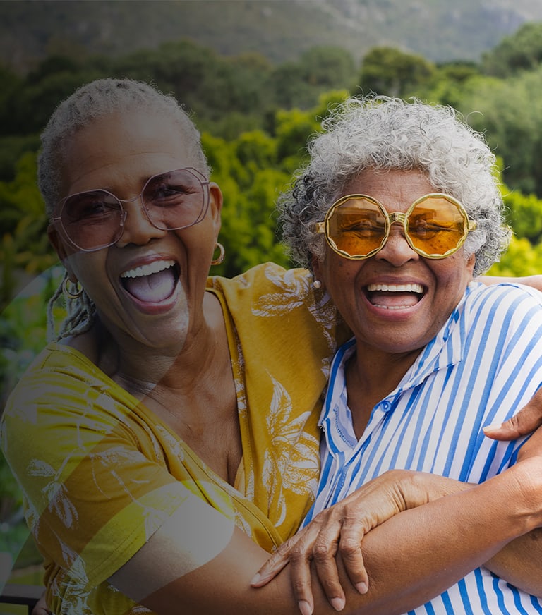 Two happy seniors embracing outdoors with sunglasses