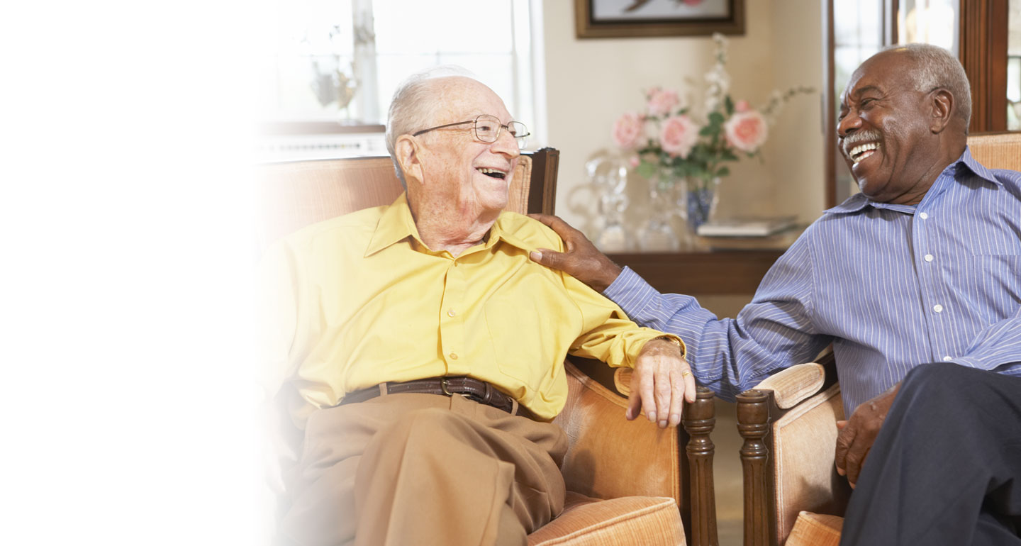 Two elderly men enjoying a conversation in a common area.