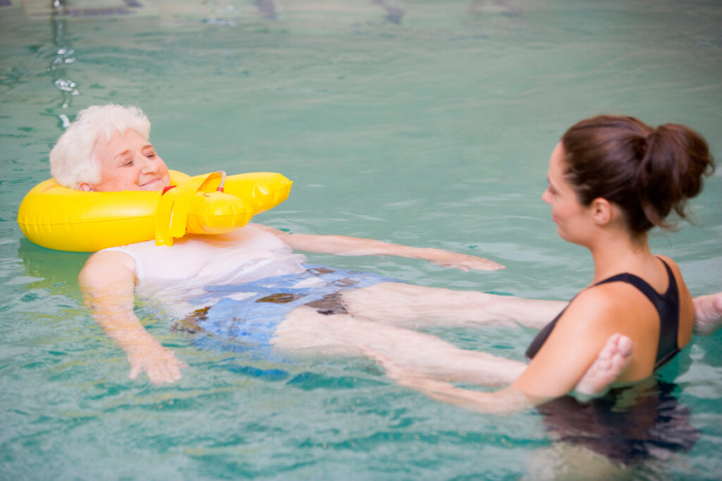 Therapist assisting resident in a pool with floatation device