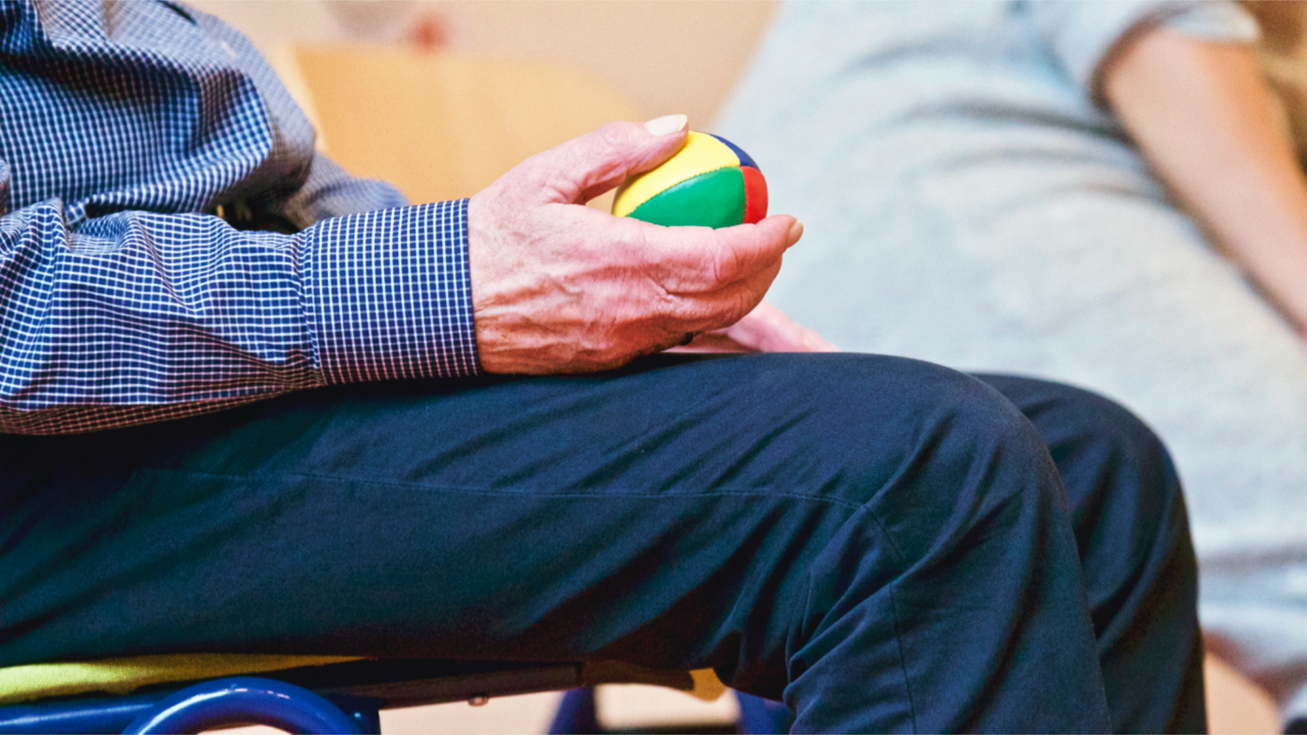 A resident holding a multi-colored stress ball during an activity