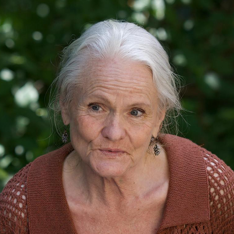 Close-up of an elderly woman smiling outdoors.