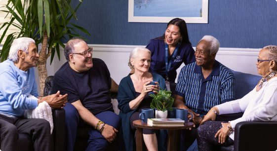 Group of residents and staff engaged in conversation.