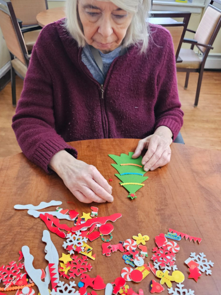 Resident creating art with decorations at a table.