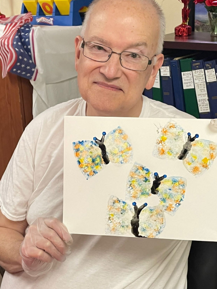 Resident showcasing their butterfly artwork during an activity.