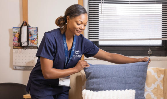 Staff member arranging cushions in a common area.